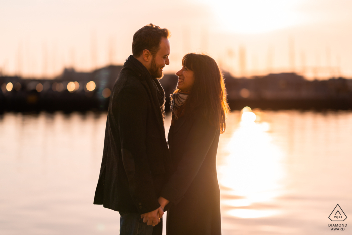 Sessione fotografica di coppie di Trieste lifestyle in Italia che mostra gli amanti che posano al tramonto vicino all'acqua