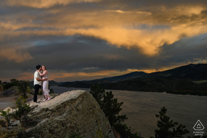 Fort Collins untraditionelles Lifestyle-Engagement-Porträt eines Paares aus Colorado, das den dramatischen Sonnenuntergang über dem Horsetooth Reservoir einnimmt