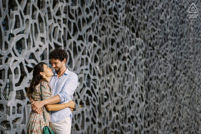 Um casal em frente a um belo prédio de arte em Marselha posando para foto de noivado