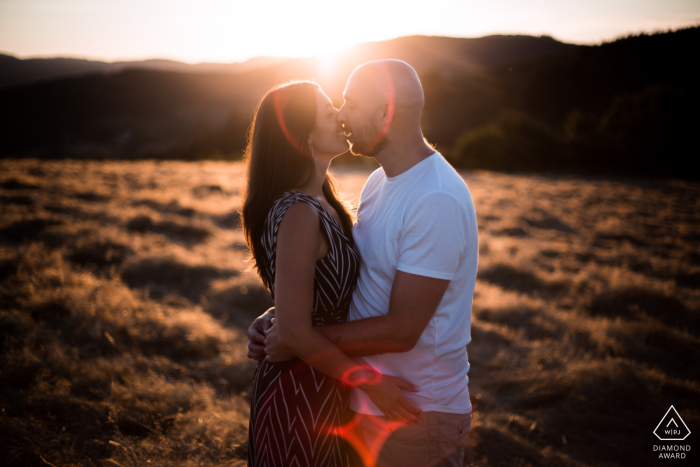 In Beaujolais, France, the couple is kissing in a field at sunset