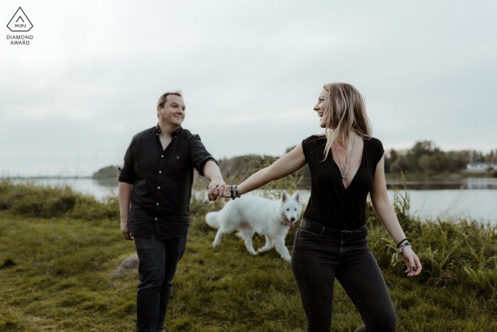 From Candes Saint Martin, France, a photo of the bride and groom strolling hand in hand on the banks of the Loire with their dog