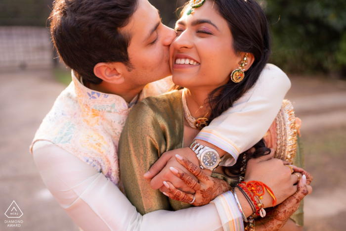 Ein verspieltes Paar umarmt und küsst sich während der Feierlichkeiten vor der Hochzeit im warmen Sonnenlicht von Chandigarh