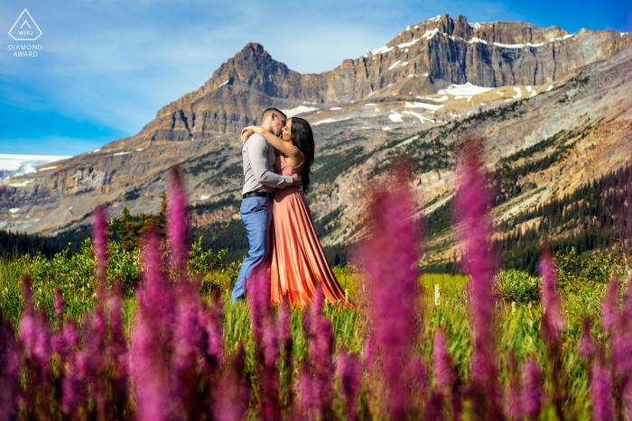 The couple's love is captured in a stunning embrace surrounded by wildflowers in shades of pink and purple at Banff National Park, AB, Canada 