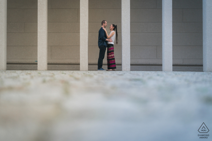 In Berlin, Germany, a couple standing in front of pillars and columns in a courtyard, surrounded by historic architecture The happy couple posed for their engagement photos in front of an ancient courtyard, surrounded by centuries-old architecture