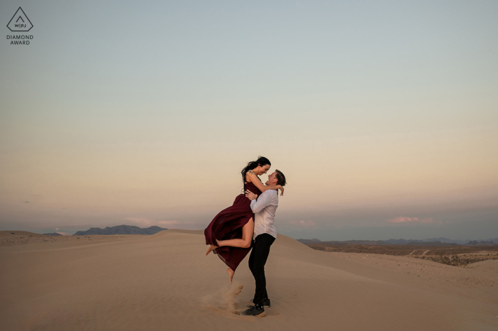 Un'immagine romantica del tardo pomeriggio è stata creata nelle sabbie del deserto, mentre un uomo sollevava la sua compagna in aria tra le dune di sabbia