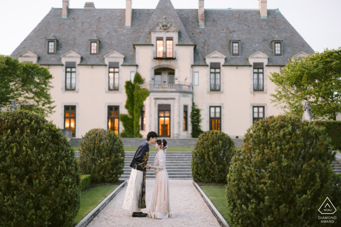 Romantico ritratto di fidanzamento catturato da un fotografo di matrimoni di Huntington, New York, al Castello di Oheka, che mostra una coppia di innamorati in abiti tradizionali cinesi che condivide un tenero bacio in un design simmetrico