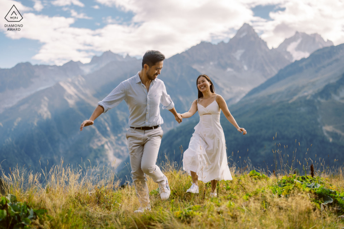 A couple joyfully runs hand in hand through the breathtaking mountains of Chamonix in the French Alps, capturing the essence of love and adventure in this stunning engagement portrait