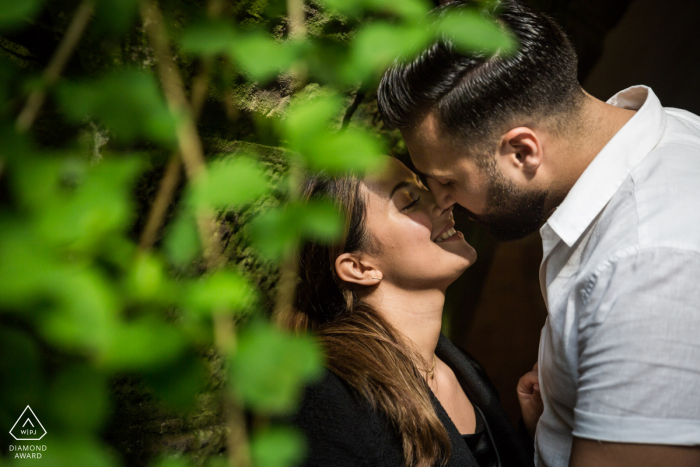 A Romantic Kiss under Central Park's Lush Greenery: An Engagement Portrait of Blissful Love Engaged couple shares a romantic kiss under the lush greenery of Central Park while celebrating their upcoming marriage.