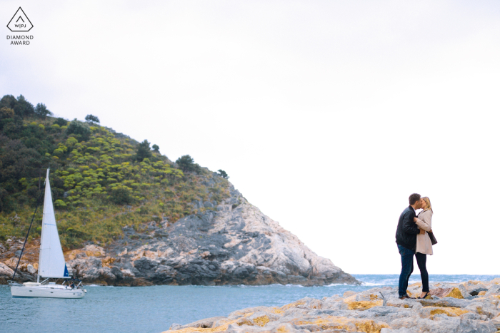 Porto Venere Engagement Pic: Romantic Love in Cinque Terre's Sparkling Waters Embraced on the rocks by the sparkling waters of Porto Venere in Cinque Terre, this couple captured the essence of romantic love in their pre-wedding portrait session.