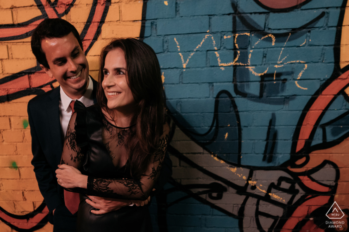 In Chicago, a couple poses for an urban-inspired portrait in a colorful alleyway adorned with eye-catching graffiti. The warm, low-lighting captures their loving embrace.