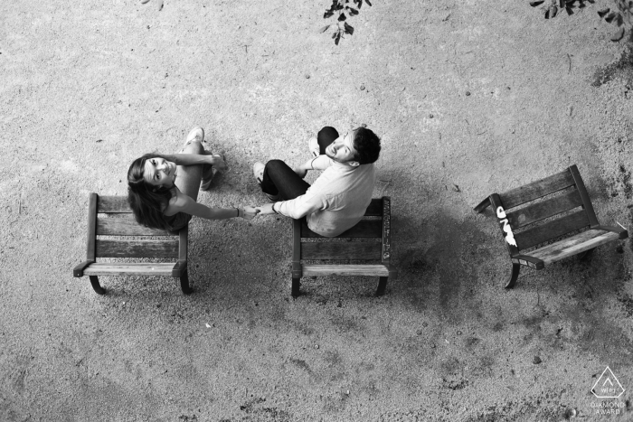 A couple poses for an engagement portrait in Toulouse's Saint Cyprien neighborhood, seated in a park and holding hands.