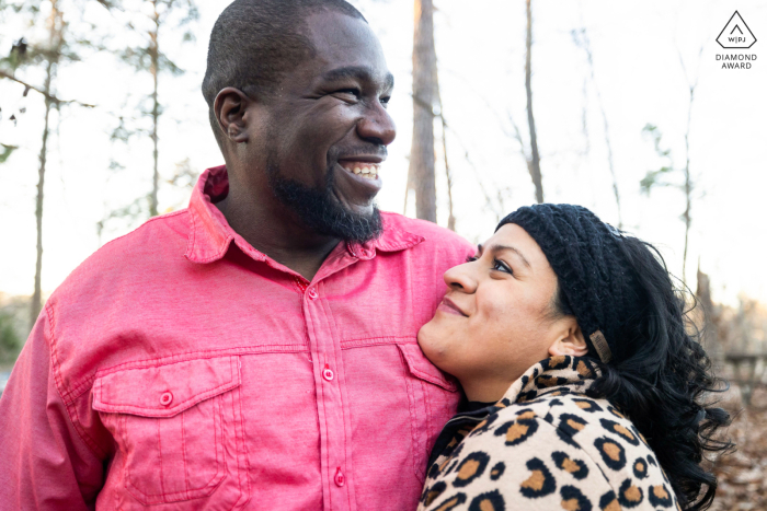 A romantic couple embraces and shares a laugh during a nature portrait session at Arabia Mountain in Georgia as they celebrate their engagement.