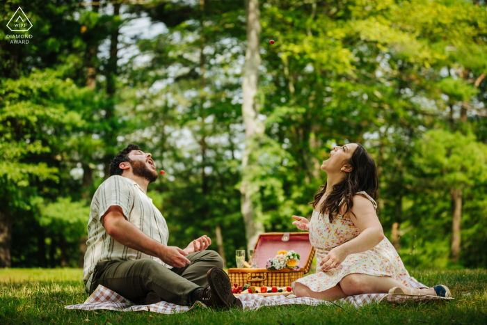 Captured amidst the park landscapes of Hudson Valley, New York, this pair playfully attempts to toss and catch juicy grapes during their enchanting engagement portrait session.