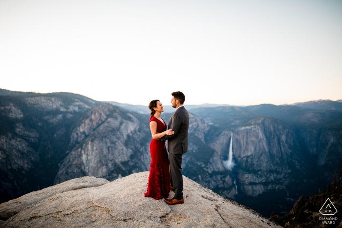 Embracing the Future in Yosemit Engaged couple embraces in the breathtaking view of Yosemite as the future awaits them on this picturesque mountaintop.