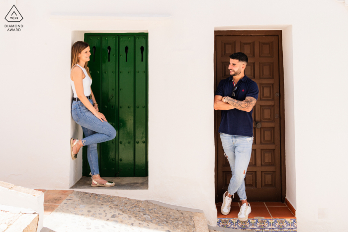 Captured by a WPJA professional at Frigiliana, Málaga, Spain, this engaging pre-wedding portrait features the soon-to-be newlyweds standing in charming village doorways, basking in the warmth of the Spanish sun against white walls.