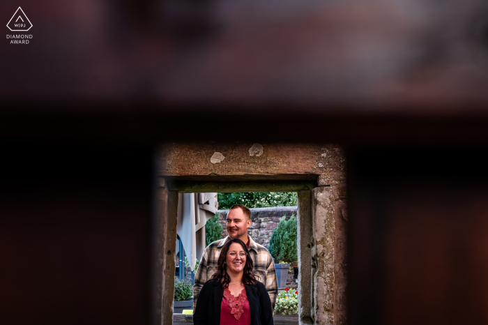 In the quaint town of Château du Haut Barr, in the French region of Alsace, a beautiful couple is peeking through a wooden door under an arch of stone. 
