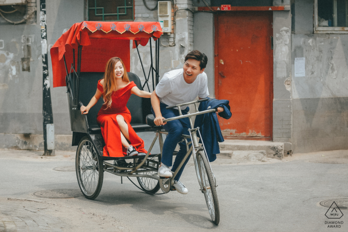 In the charming alleyways of a Beijing hutong, a man happily pedals a bike taxi while his fiancée enjoys the ride, capturing the joy of their adventure.