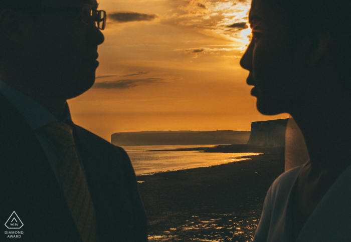 Capturing the essence of love at sunset, the happy couple strikes a pose during their pre-wedding portrait session by the water. In a beautiful display of affection, the pair's silhouettes create a romantic scene against the stunning backdrop.
