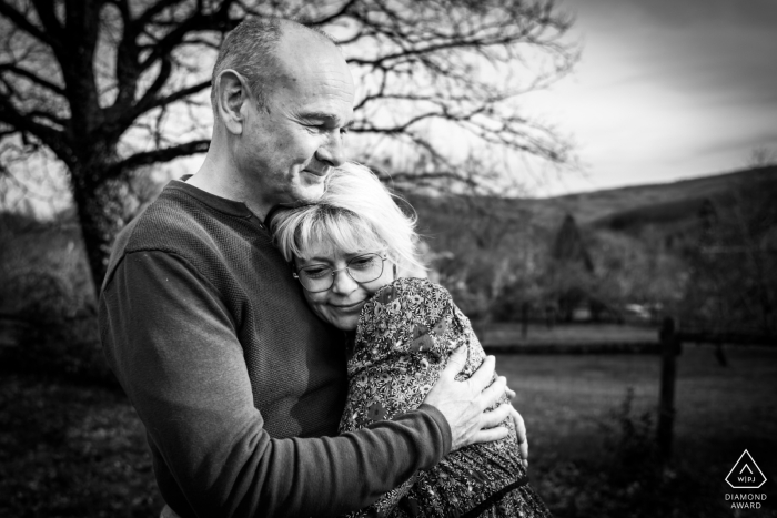 Black-and-White Portrait in Anost's Natural Setting, Radiating Warmth Black-and-white portrait of a couple holding each other tightly in front of a tree in Anost, exuding warmth and affection.
