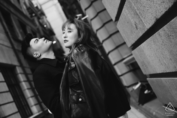 Fashion-forward couple in sleek black outfits, standing confidently in the bustling urban streets of the Bund, Shanghai, China.