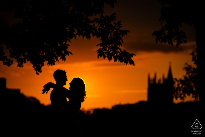 At Northwestern University in Evanston, IL, a couple's silhouette is captured at sunset, creating a stunning engagement photo against the vibrant sky.