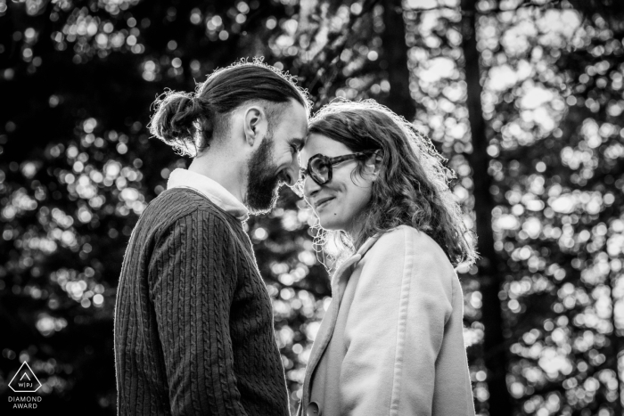 In Carnaval de Pierres, Uchon, a couple stands head to head in a black-and-white shot. Captured from a low angle, the trees behind them create a dramatic and intimate forest scene.