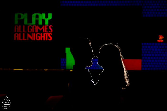 A Toronto couple's romantic silhouette against the bright lights of a lively arcade.