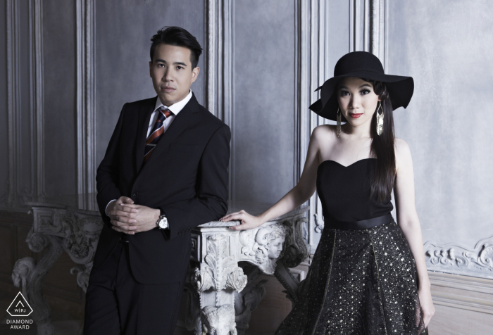In Bangkok, Thailand, a couple exudes elegance in formal clothing, both looking directly at the camera. This sophisticated portrait is expertly captured by a skilled WPJA photographer.