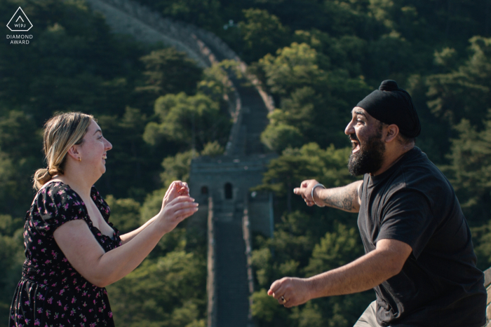 A couple joyfully react to each other on Mutianyu Great Wall in Beijing, surrounded by stunning ancient scenery.