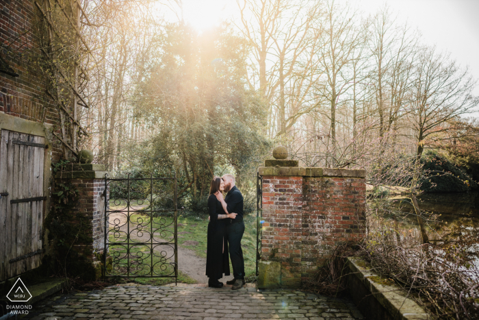 An engaged couple poses at a gate of an old castle in Münsterland, Germany.