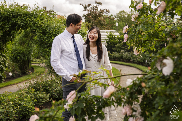 BOSTON — Surrounded by blooming roses at the Kelleher Rose Garden, a cheerful couple shares a laugh during their engagement session, their joy shining through this romantic portrait.