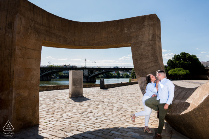Engagement portrait in Seville, Spain: a couple poses for a pre-wedding photo at a historic stone monument.
