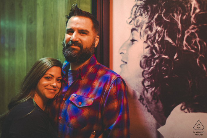 At Geraci's Slice Pizza in Cleveland, OH, the couple stands near a cozy corner of their favorite pizza shop, beside a large portrait of a girl on the wall.