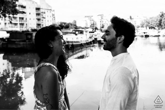 At Port de Ramonville, France, the couple stands face to face in profile by the water, captured in a black-and-white shot highlighting their quiet connection.