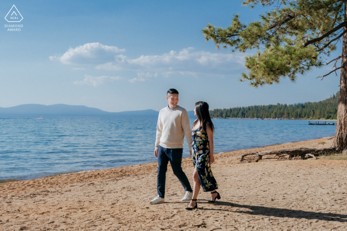At South Lake Tahoe, CA, the couple walk hand in hand along the shore, with brilliant blue water and sky creating a stunning backdrop to their proposal. 
