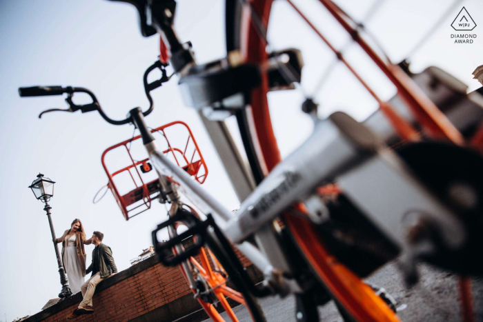 In Florence, Italy, a couple poses for a portrait framed by the city, with bicycles and lampposts in the background.