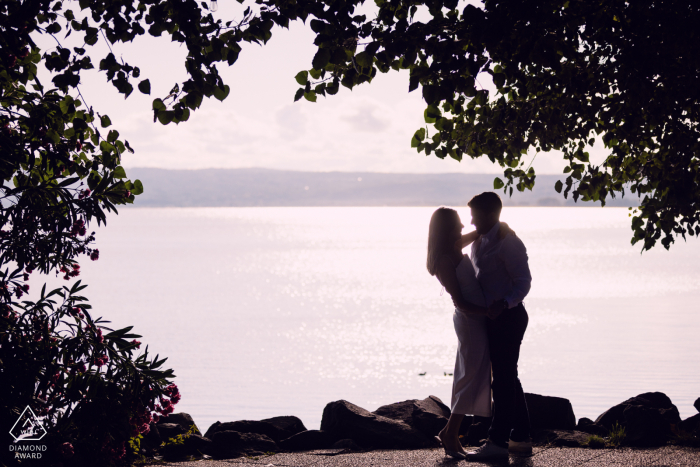 The dramatic silhouette of the couple is captured against the shimmering water at Lago di Bolsena, Italy, during a breathtaking sunset that emphasizes their romantic and lasting engagement bond.