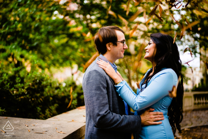 Soft smiles are shared between the engaged couple as autumn leaves drift around them in Rittenhouse Square, Philadelphia, capturing a peaceful and seasonal engagement portrait in the heart of Pennsylvania.