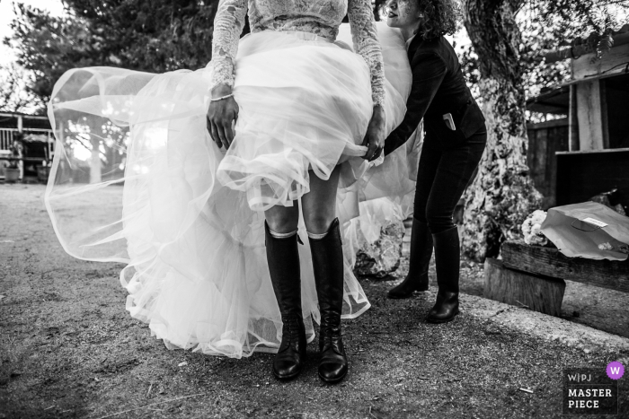 Italy bride trying to fix her dress over equestrian boots outside at the wedding