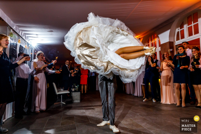 Photo by: <a href="https://www.wpja.com/contests/2018-v01-photography-competition/best-wedding-photographers/2166016">Indra Simons - Enschede Overijssel</a> Overjissel wedding photographer captured this image of a bride in mid twirl with her feet off the ground as she and her groom have their first dance in front of wedding guests