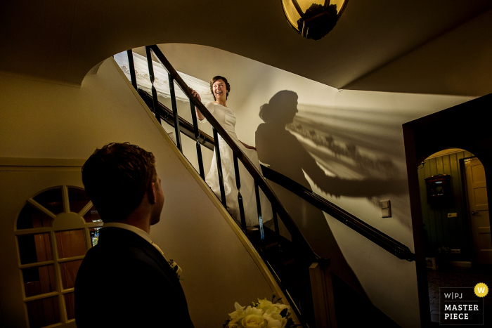 Photo by: <a href="https://www.wpja.com/contests/2018-v01-photography-competition/best-wedding-photographers/2166066">Damon Pijlman - Wassenaar Zuid Holland</a> Netherlands wedding photographer captured this photo of a bride walking down a curved staircase as her groom waits at the bottom