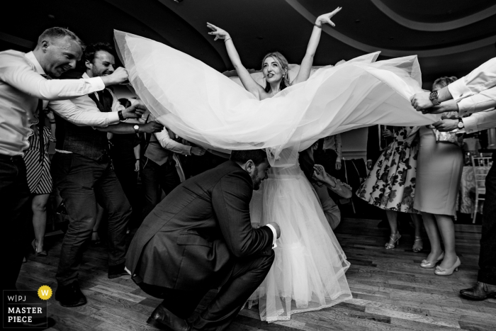 Photo by: <a href="https://www.wpja.com/contests/2018-v01-photography-competition/best-wedding-photographers/2167081">Kevin Kheffache - Dun Laoghaire Dublin</a> Dublin guests hold up part of the brides dress while the groom is underneath it