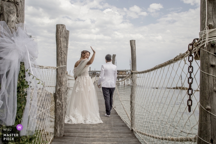 Foto von: <a href="https://www.wpja.com/contests/2018-v01-photography-competition/best-wedding-photographers/2169696"> Damiano Fantini - Chieti Chieti </a> Abruzzobraut winkt, während sie und der Bräutigam die Hochzeit verlassen