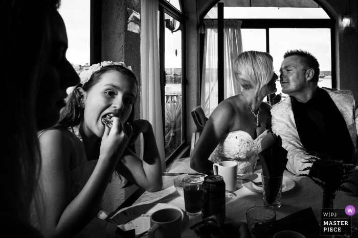 Photo by: <a href="https://www.wpja.com/contests/2018-v01-photography-competition/best-wedding-photographers/2170316">Miguel Onieva - Madrid Madrid</a> Arguineguin bride and groom about to kiss while girl eats next to them