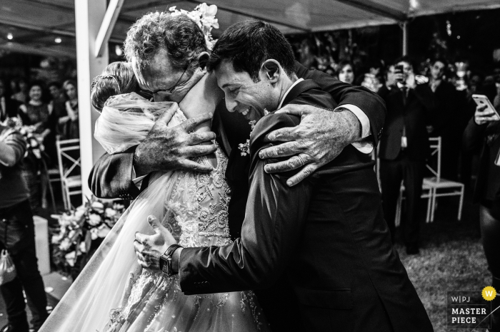 Photo by: <a href="https://www.wpja.com/contests/2018-v01-photography-competition/best-wedding-photographers/2173266">Vinicius Fadul - Campinas São Paulo</a> Americana brides father hugs her and the groom at the wedding reception