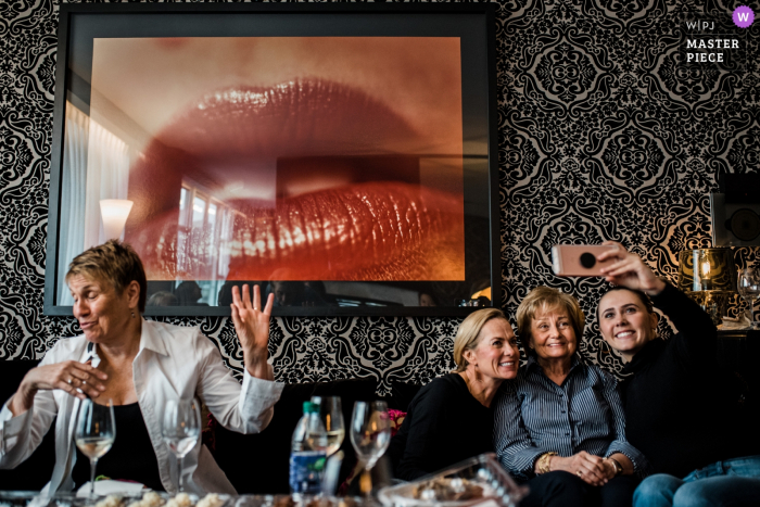 Photo by: <a href="https://www.wpja.com/contests/2018-v01-photography-competition/best-wedding-photographers/2174416">Justine Boulin - Coquitlam British Columbia</a> opus hotel, Vancouver, BC - British Columbia Wedding Photo of guests with selfie poses and wall art of lips