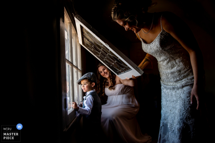 New Jersey boy looks out the window with the bride and maid of honor before the wedding