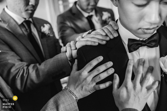 Photo by: <a href="https://www.wpja.com/contests/2018-v01-photography-competition/best-wedding-photographers/2174951">Ken Pak - Washington DC District Of Columbia</a> Centreville, Virginia groomsmen put their hands on the groom and pray before the wedding
