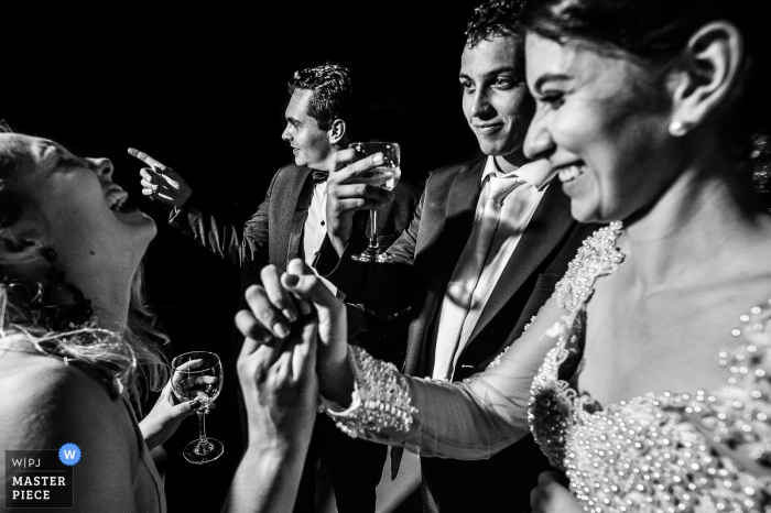 Photo by: <a href="https://www.wpja.com/contests/2018-v02-photography-competition/best-wedding-photographers/2182046">Vinicius Fadul - Campinas São Paulo</a> Vicosa bride and maid of honor hold hands and laugh with drinks at the wedding reception