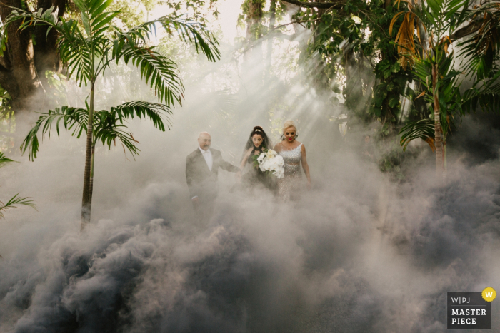 Foto door: <a href="https://www.wpja.com/contests/2018-v03-photography-competition/best-wedding-photographers/2186401"> Lukas Guillaume - Miami Florida </a> Miami, Florida bruid loopt met haar moeder en vader in de mist en bomen